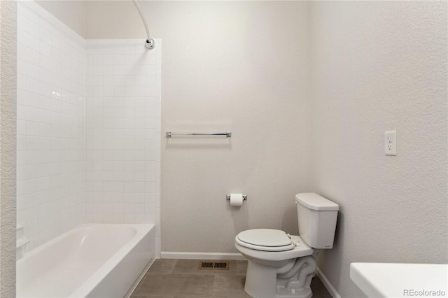 bathroom with tiled shower / bath combo, toilet, and tile patterned flooring