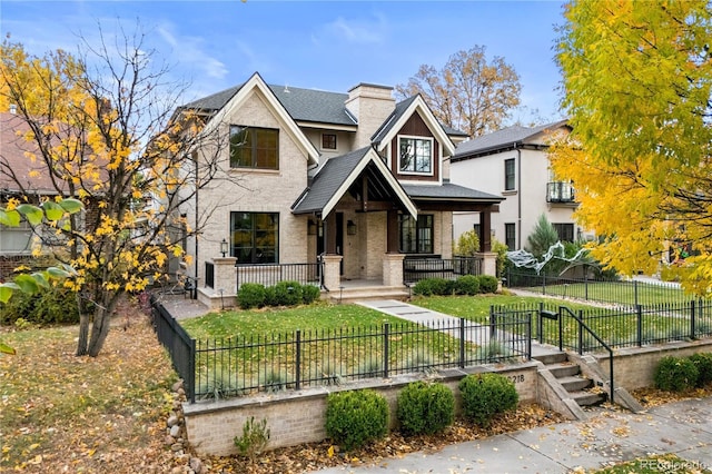 view of front facade featuring a fenced front yard, roof with shingles, covered porch, a front lawn, and brick siding