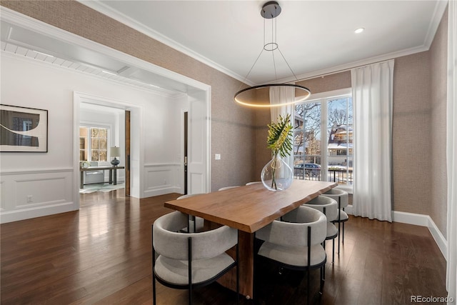 dining room with dark wood-style floors, a decorative wall, crown molding, and a wainscoted wall