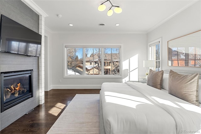 bedroom with a large fireplace, multiple windows, ornamental molding, and dark wood-style flooring