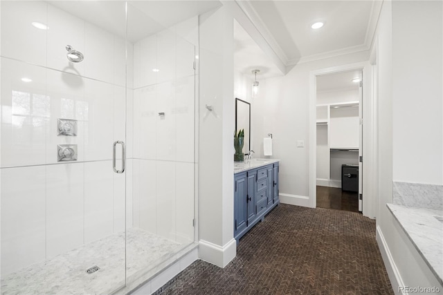 bathroom with a walk in closet, crown molding, a stall shower, vanity, and baseboards