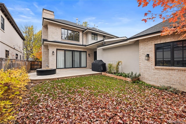 back of house with a patio area, brick siding, a chimney, and fence