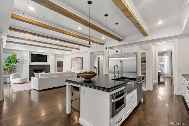 2218 S Clayton St, Denver, CO 80210 - kitchen with stainless steel appliances, dark countertops, a sink, a breakfast bar area, and beamed ceiling