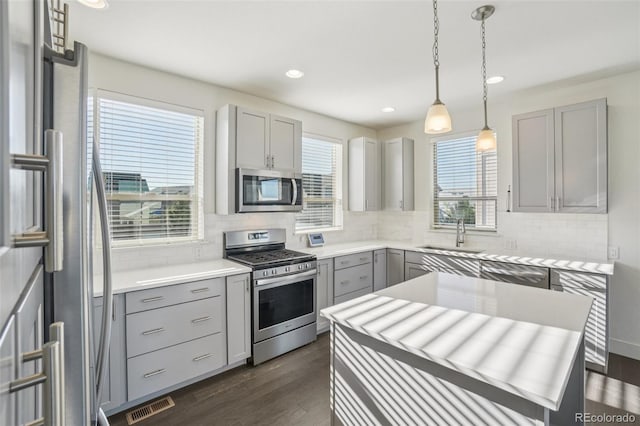 5668 Galena St, Denver, CO 80238 - kitchen featuring appliances with stainless steel finishes, gray cabinetry, dark wood-style flooring, decorative backsplash, and recessed lighting