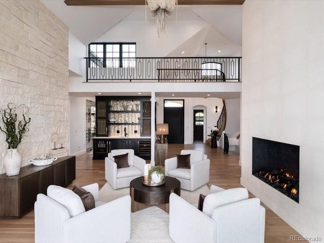 860 Diamond Ridge Cir, Castle Rock, CO 80108 - living room featuring a lit fireplace, high vaulted ceiling, wood finished floors, a bar, and arched walkways