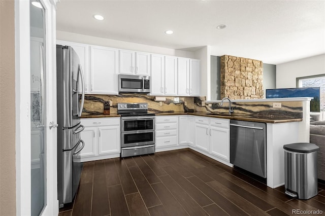 kitchen featuring stainless steel appliances, backsplash, dark countertops, and a sink