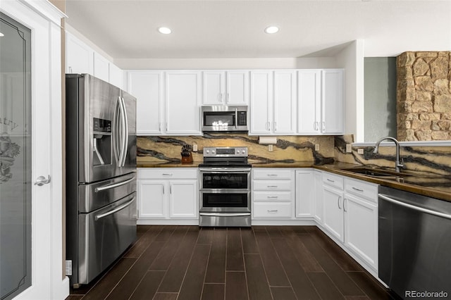 kitchen with appliances with stainless steel finishes, dark countertops, a sink, and tasteful backsplash