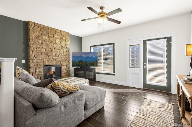 living area featuring ceiling fan, a fireplace, baseboards, and wood finished floors