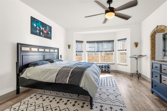 bedroom with light wood-type flooring, ceiling fan, and baseboards