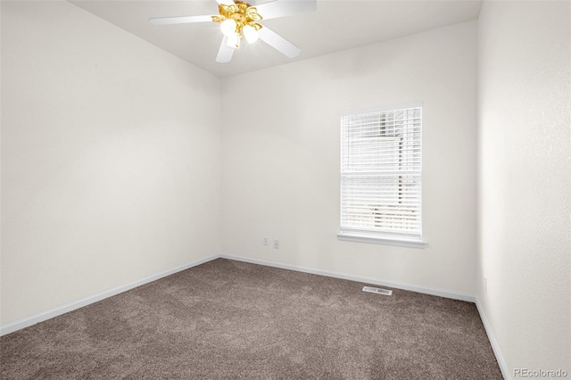 carpeted spare room featuring visible vents, baseboards, and a ceiling fan