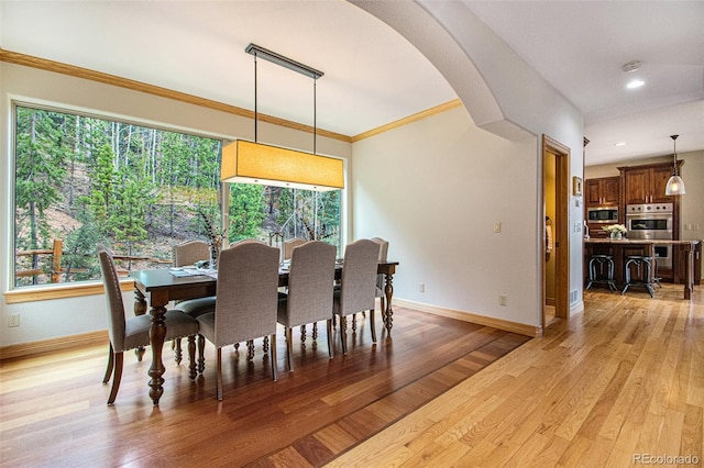 dining room with plenty of natural light, ornamental molding, and light wood-type flooring