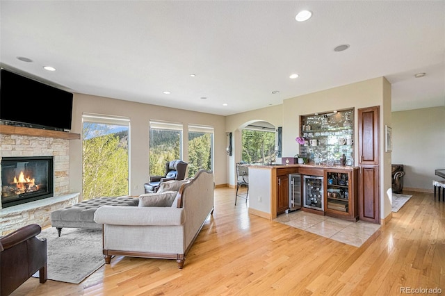 living room featuring bar, a fireplace, light hardwood / wood-style floors, and beverage cooler