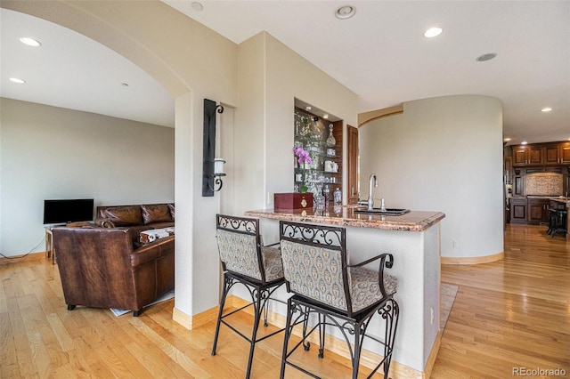 kitchen featuring light hardwood / wood-style floors, sink, a kitchen breakfast bar, and kitchen peninsula