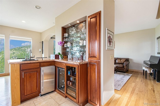 bar featuring sink, high quality fridge, wine cooler, and light hardwood / wood-style flooring