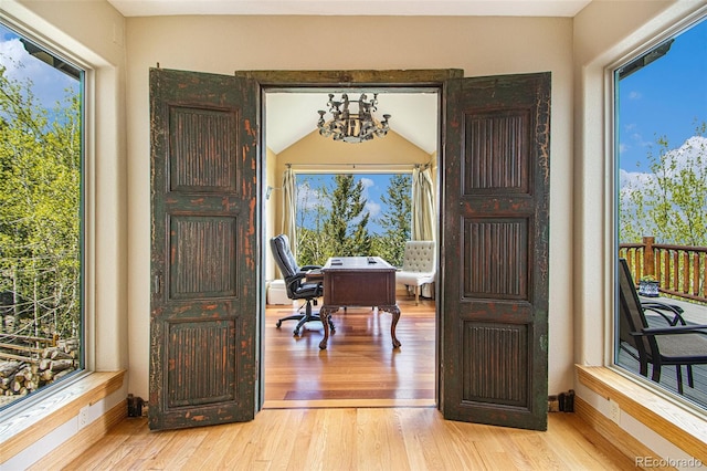 office space featuring plenty of natural light, a chandelier, and light wood-type flooring