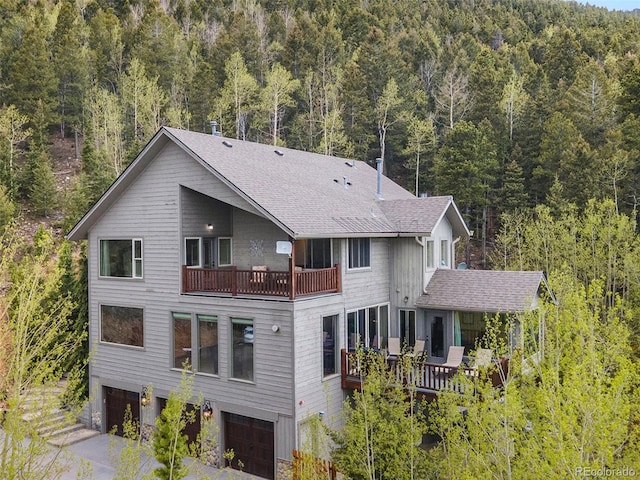 rear view of property with a garage and a balcony