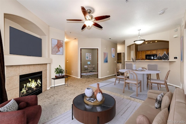 carpeted living room with ceiling fan and a tile fireplace