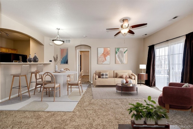 carpeted living room with ceiling fan