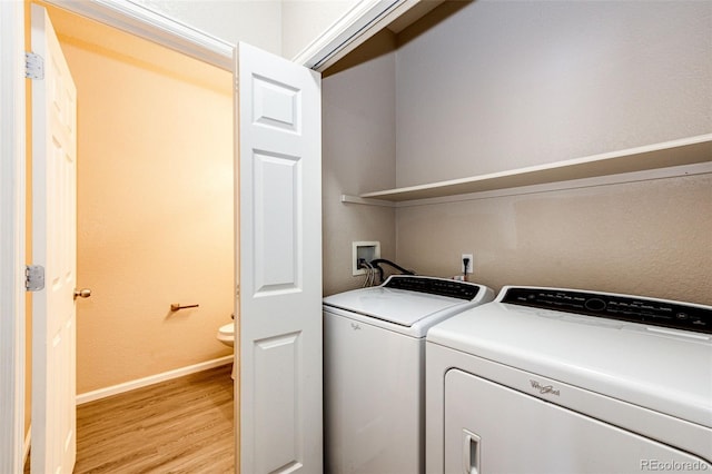 laundry room with washing machine and dryer and light hardwood / wood-style flooring