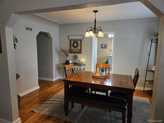 148 15th St, Burlington, CO 80807 - dining space featuring a textured wall, arched walkways, wood finished floors, and a chandelier