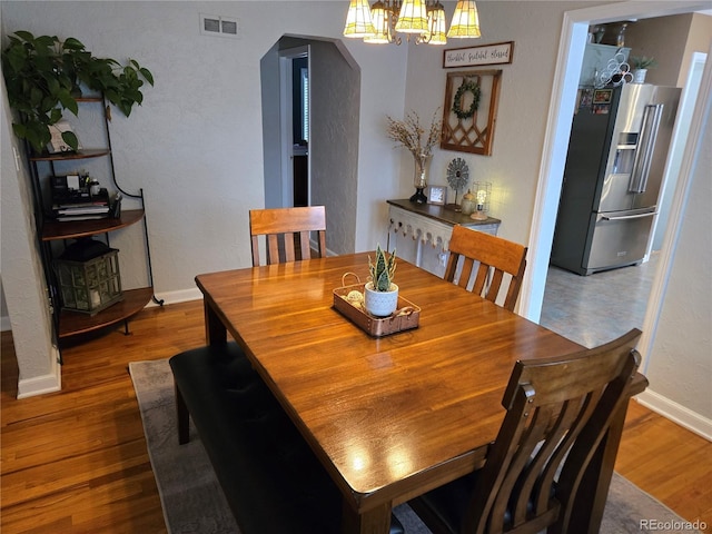 148 15th St, Burlington, CO 80807 - dining area with arched walkways, a chandelier, and wood finished floors