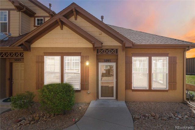 5895 S Taft Ct Unit H, Littleton, CO 80127 - exterior entry at dusk with a shingled roof and stucco siding