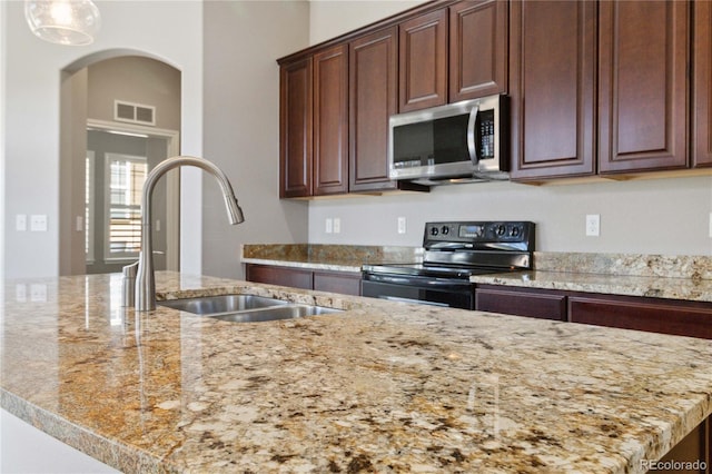 5895 S Taft Ct Unit H, Littleton, CO 80127 - kitchen with stainless steel microwave, electric range, a sink, arched walkways, and light stone countertops