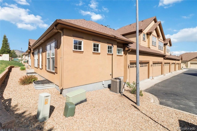 5895 S Taft Ct Unit H, Littleton, CO 80127 - view of property exterior with stucco siding, cooling unit, driveway, and a garage