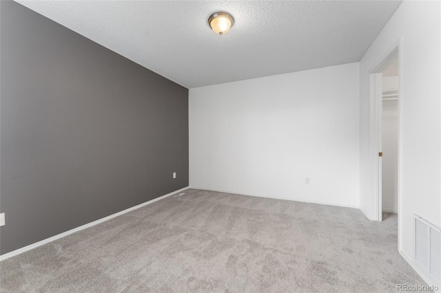 carpeted spare room with a textured ceiling