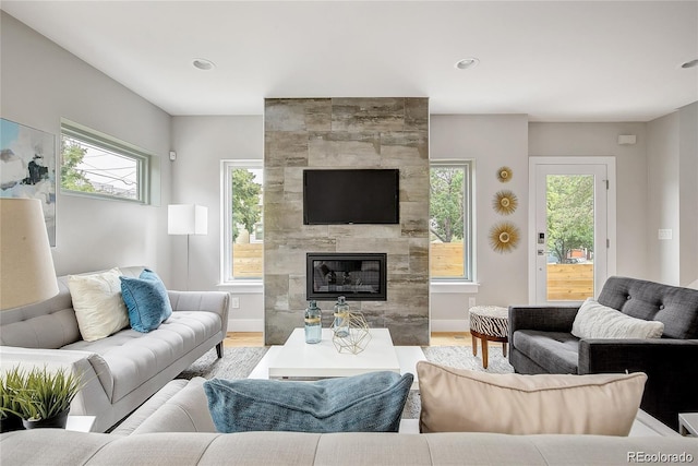 living room with wood-type flooring and a tiled fireplace