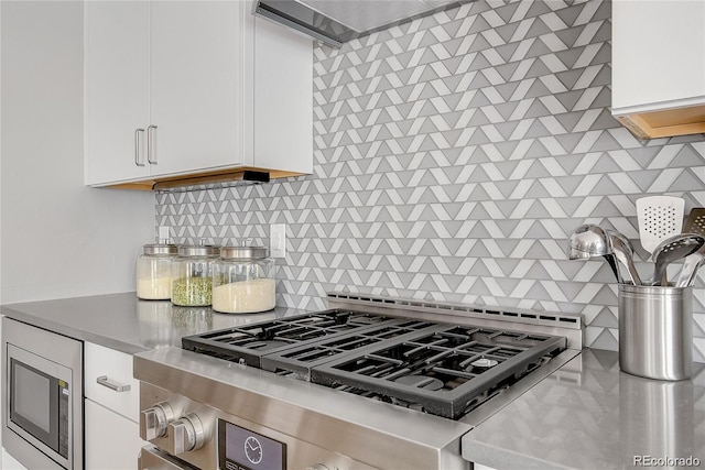 kitchen with stainless steel appliances, white cabinetry, and backsplash