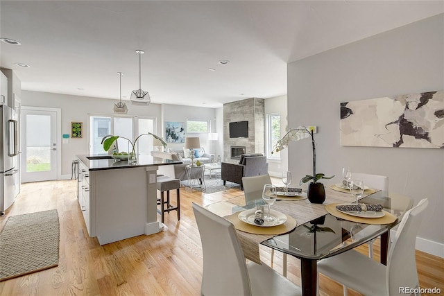 dining space with sink, a fireplace, and light hardwood / wood-style flooring