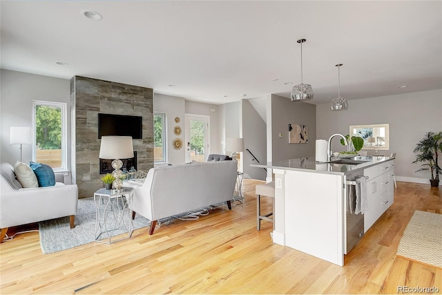 kitchen with pendant lighting, sink, light hardwood / wood-style floors, an island with sink, and white cabinets