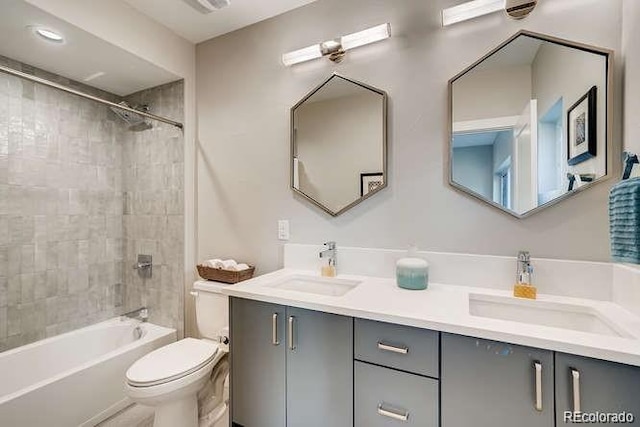 full bathroom featuring vanity, tiled shower / bath combo, and toilet