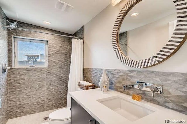 bathroom with tile walls, vanity, toilet, and a shower with shower curtain