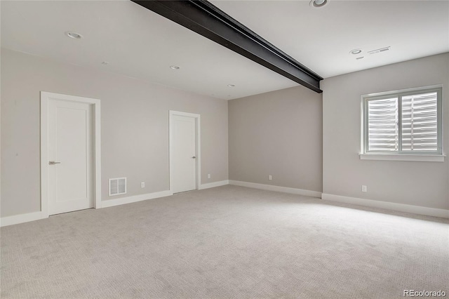 unfurnished room with beamed ceiling and light carpet