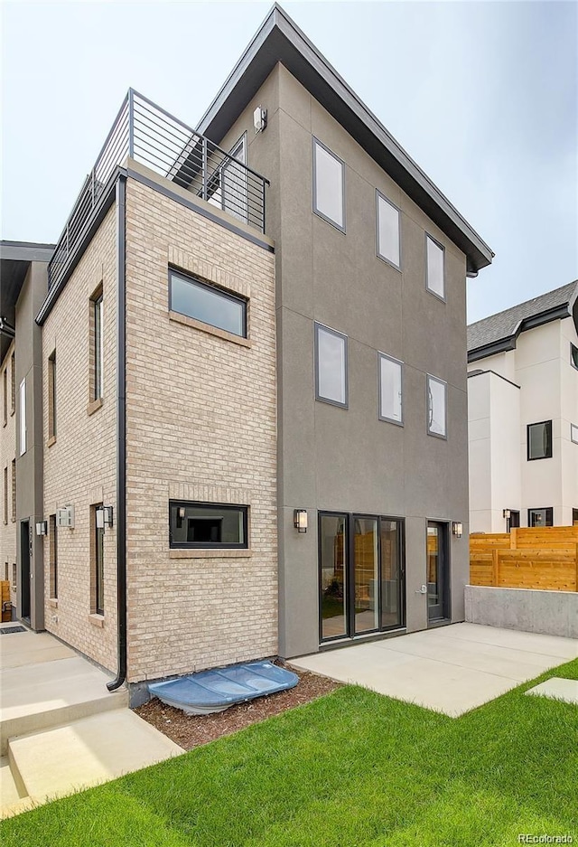 back of house featuring a balcony, a yard, and a patio area