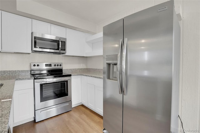 kitchen with white cabinetry, light stone counters, light hardwood / wood-style flooring, and stainless steel appliances