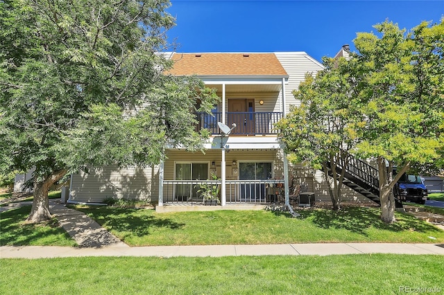 view of front of property with a balcony, a front yard, covered porch, and cooling unit