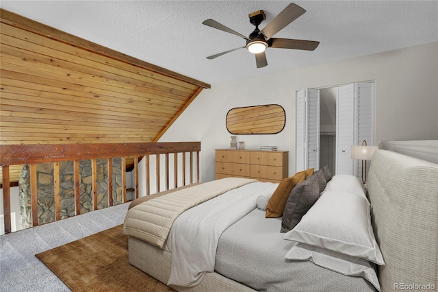 bedroom featuring lofted ceiling, carpet flooring, ceiling fan, a textured ceiling, and a closet