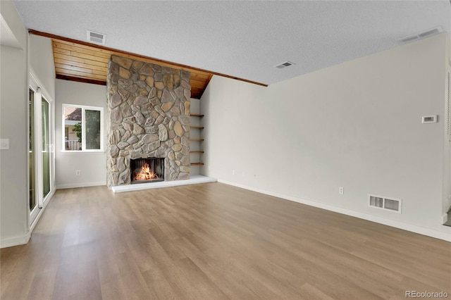 unfurnished living room with lofted ceiling with beams, wood ceiling, a fireplace, and light hardwood / wood-style floors