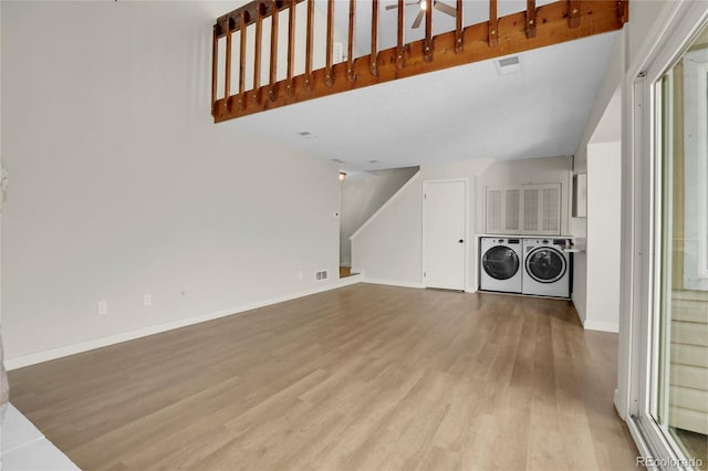 laundry area with washing machine and clothes dryer and light hardwood / wood-style flooring