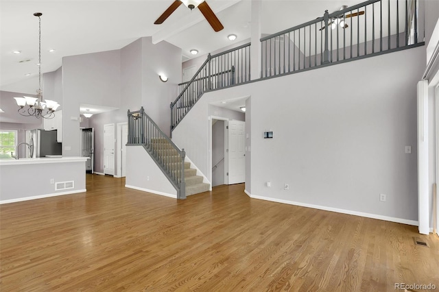 20394 E Colgate Pl, Aurora, CO 80013 - unfurnished living room featuring a ceiling fan, high vaulted ceiling, stairs, baseboards, and light wood-style flooring