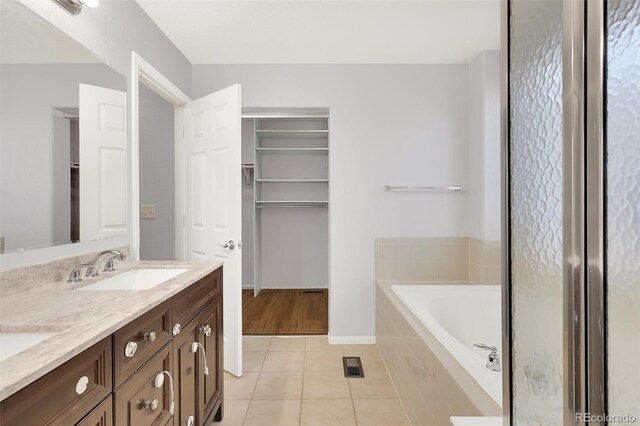 20394 E Colgate Pl, Aurora, CO 80013 - bathroom featuring tile patterned flooring, a garden tub, double vanity, a spacious closet, and baseboards