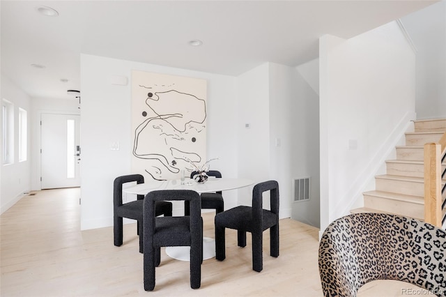 dining space featuring stairway, light wood-style flooring, and visible vents