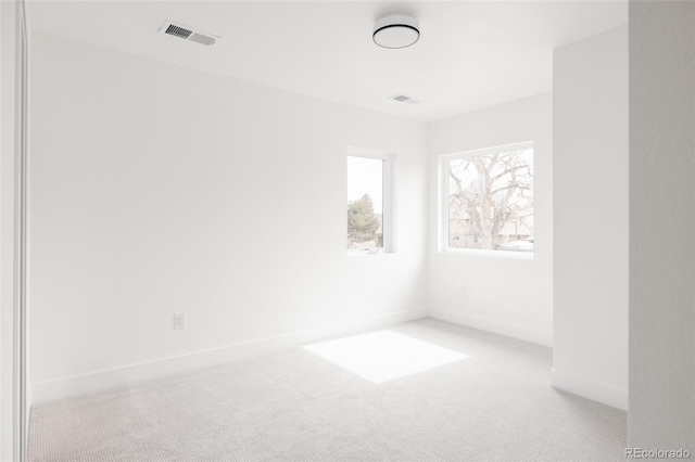 spare room featuring light carpet, visible vents, and baseboards