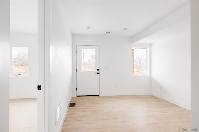 doorway to outside with light wood-type flooring, visible vents, and baseboards