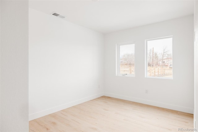 unfurnished room featuring light wood finished floors, visible vents, and baseboards