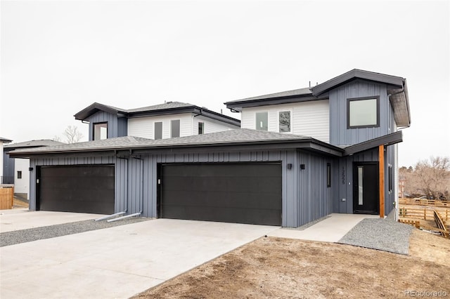 view of front of house with an attached garage, driveway, a shingled roof, and board and batten siding