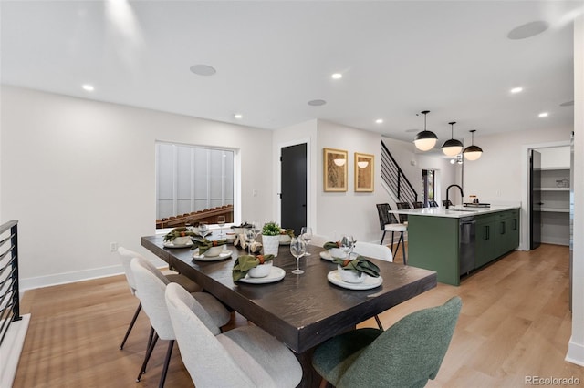dining area featuring light wood finished floors, recessed lighting, baseboards, and stairs